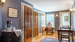 A hallway with wooden doors, a rug, a chair, and a table with a pitcher and cups. - Waterfront, Swimming Hotspot, Private Down Town Location, Farmhouse (Waitsfield)