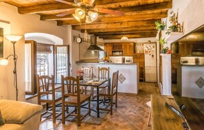 A cozy kitchen with wooden cabinets, a dining area with a table and chairs, and a ceiling fan.