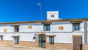 Un edificio blanco con detalles de piedra, una entrada central y múltiples ventanas.