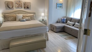 Ein Schlafzimmer mit einem großen Bett, einem Nachttisch, einer Lampe und einer Wand mit gerahmten Kunstwerken.