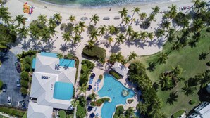 Ein Luftbild eines Resorts mit großem Schwimmbad, Strand und Palmen.