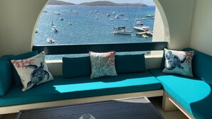 Ein gemütlicher Sitzbereich mit Meerblick, inklusive einer Couch mit Meeresschildkröten-Kissen und einem kleinen Tisch mit einer dekorativen Vase.