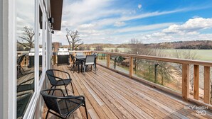 Eine Holzterrasse mit Gartenmöbeln, einem Grill und einem schönen Blick auf eine hügelige Landschaft.