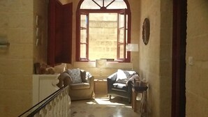 Eine schmale Treppe führt zu einem Wohnbereich mit zwei Sofas, einem kleinen Tisch und einer Lampe.