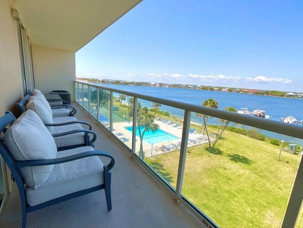 A balcony with a row of chairs and a view of a swimming pool and beach. - Sabine 4D Waterfront Condo Sleeps 6, Corner Unit - Pool (Pensacola Beach)