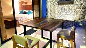 A room with a wooden table, two chairs, a bed with a patterned headboard, and a blue accent wall. - Amazing right on the water, BEACHFRONT studio near Tamarindo (POTRERO)