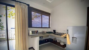 A compact kitchen with a refrigerator, microwave, sink, and a window with blinds. - Amazing right on the water, BEACHFRONT studio near Tamarindo (POTRERO)