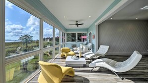 Una habitación amplia con ventanas grandes, ventilador de techo y asientos modernos.