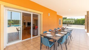 A dining area with a table set for six, a pool in the background, and a sliding glass door leading to a living room. - Fidalsa Dom Perignon (Crevillente)