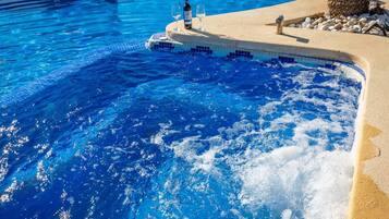 Une piscine à l’eau d’un bleu cristallin, une petite île avec une bouteille et un verre, et un palmier.