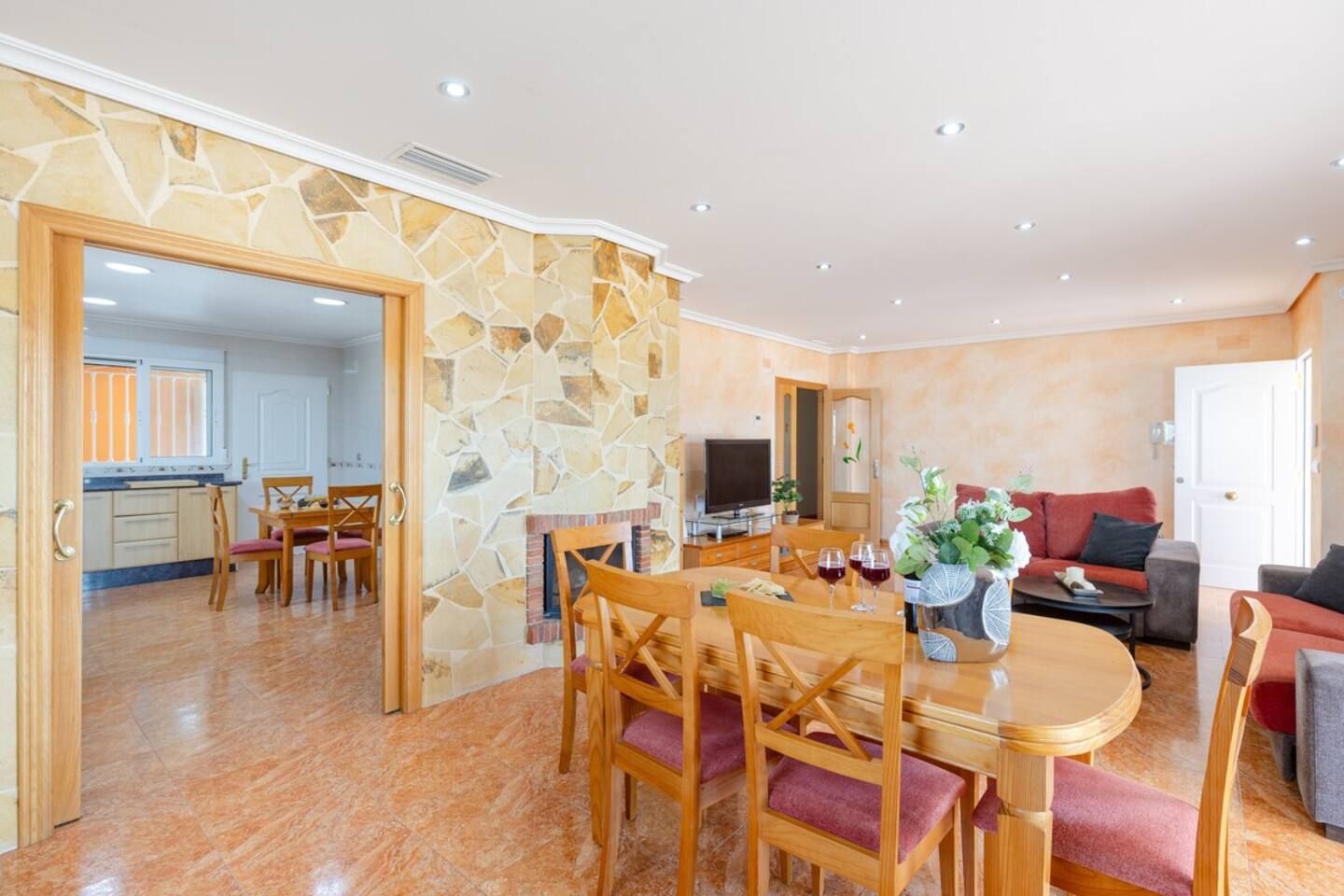 Un espace repas avec un mur en pierre, des meubles en bois et un téléviseur.