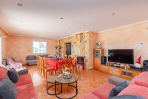 Een ruime woonkamer met een open haard, een eethoek en een televisie.