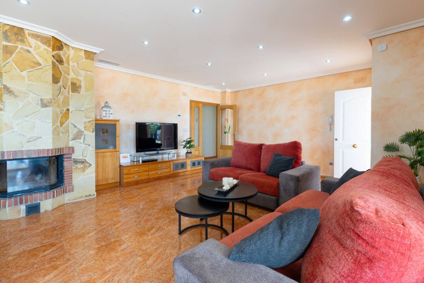 Un salon avec une cheminée en pierre, un téléviseur, un canapé et une table basse.