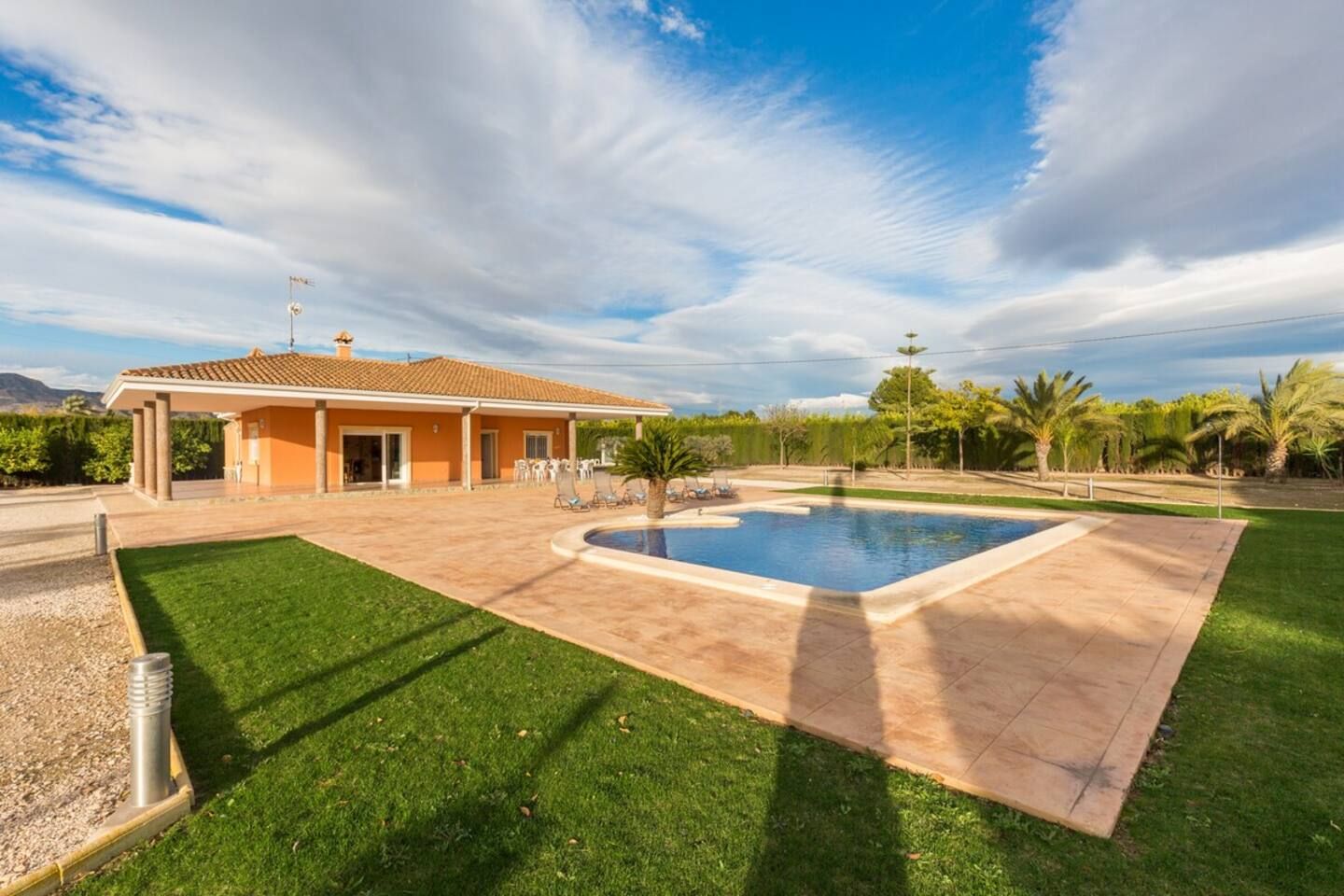 Une propriété résidentielle dotée d’une piscine, d’un patio couvert et d’une pelouse bien entretenue.
