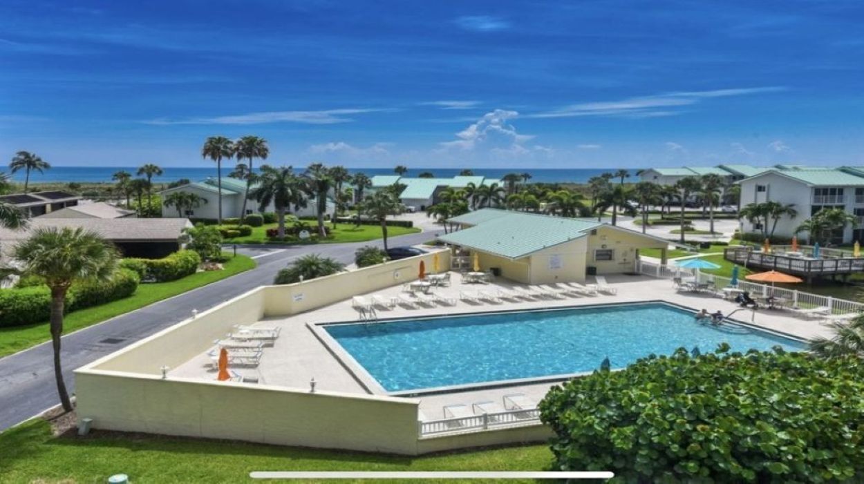 A resort with a swimming pool, palm trees, and a view of the ocean.