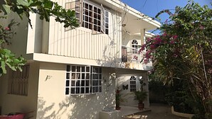 A two-story house with a balcony, large windows, and potted plants. - Vacation rental house (Arrondissement de Jacmel)