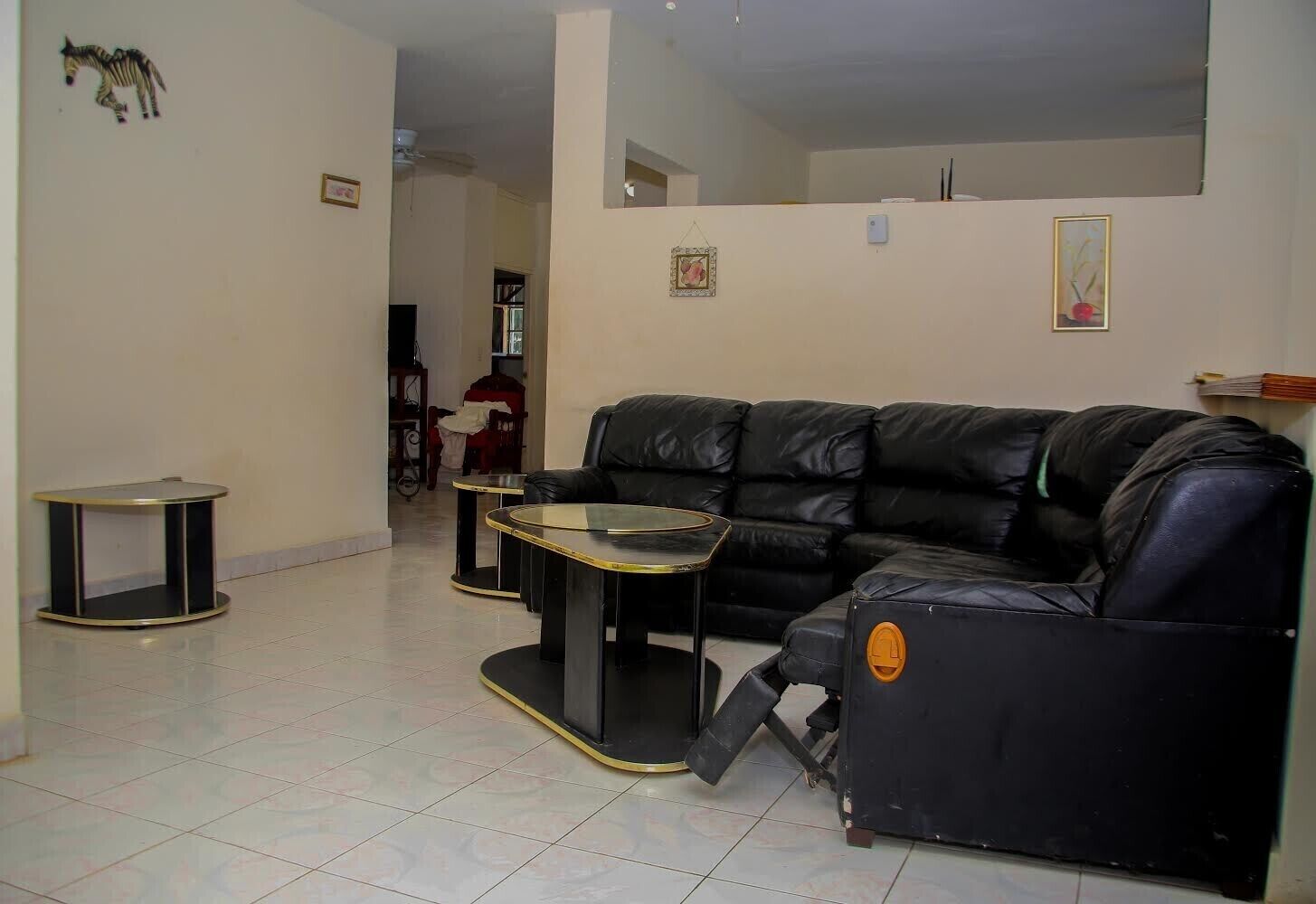 A living room with a black leather sofa, two glass-top coffee tables, and a small black side table.