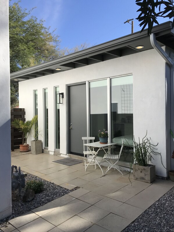 A modern building with large glass doors, a white exterior, and a patio area with a table and chairs.
