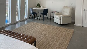 Ein modernes Schlafzimmer mit einem großen Bett, einem Deckenventilator, einem Fernseher und einer Sitzecke mit Tisch und Stühlen.