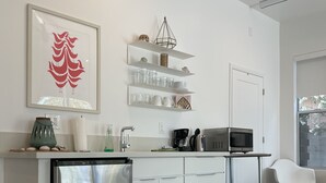 Eine moderne Küche mit weißen Schränken, einem Edelstahlkühlschrank und einer Kaffeemaschine.