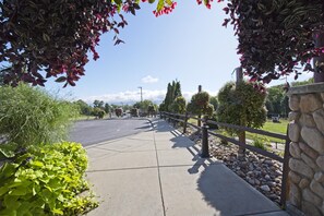 Stroll along the beautifully landscaped sidewalk, lined with lush greenery and a stone wall.