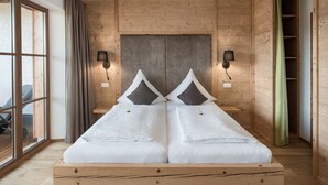 Een tweepersoonsbed met houten frame, twee nachtkastjes, een hoofdbord en twee wandlampen.