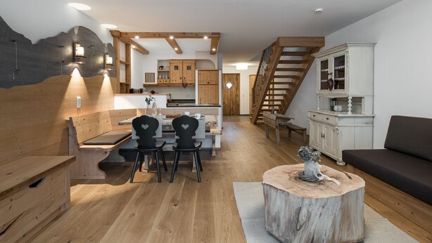 Een modern interieur met een houten eethoek, een trap en een gezellige zithoek.