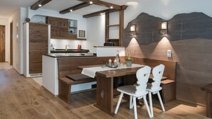 Eine gemütliche Küche mit Holzschränken, einer integrierten Bank und einem Esstisch mit weißen Stühlen.