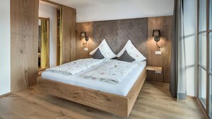 Ein modernes Schlafzimmer mit einem hölzernen Bettgestell, zwei Nachttischen mit Lampen und einem großen Fenster.