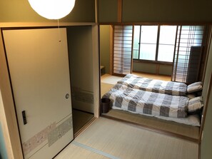Una tradizionale stanza giapponese con pavimento in tatami, paravento shoji e futon.