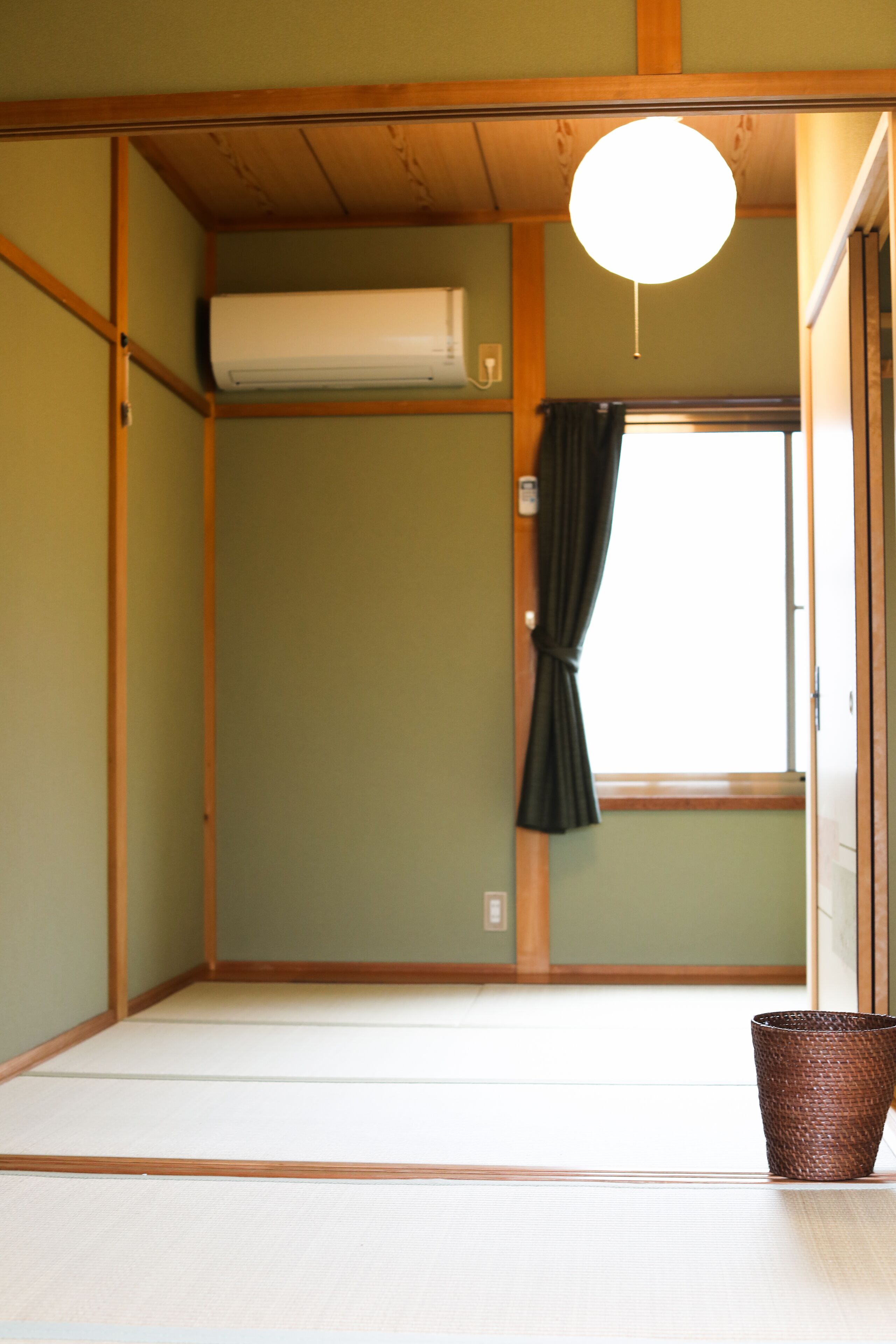 Ett traditionellt japanskt rum med tatamimattor på golvet, en skjutdörr och en hängande lampa.
