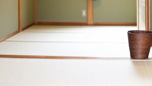 Um quarto japonês tradicional com tatames, uma porta deslizante e um candeeiro suspenso.