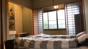 Quarto tradicional em estilo japonês, com tatames, um painel shoji, uma cama futon e um shoji pendurado.