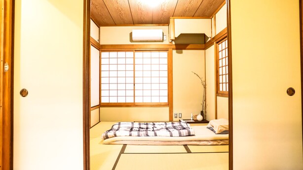 A traditional Japanese room with tatami flooring, a futon bed, sliding doors, and a shoji screen. - Kyomusha Inn (Kyoto)
