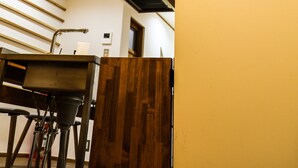 A hotel interior with a wooden staircase, a sink, and a bicycle. - Kyomusha Inn (Kyoto)