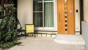 A hotel entrance with a wooden door, a sliding glass door, and a small outdoor seating area. - Kyomusha Inn (Kyoto)
