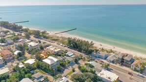 An aerial view of a coastal town with a beach, clear blue waters, and a pier extending into the sea. - Sleeps 10  Beach-Bay Views Private Heated Pool Elevator Perfect location (Holmes Beach)