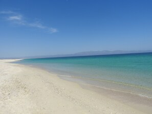 En strand med krystalklart turkis vand og en sandbund.