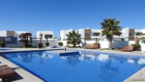 A swimming pool with lounge chairs and a children's play area. - House 255 Torres Cantera (La Paz)