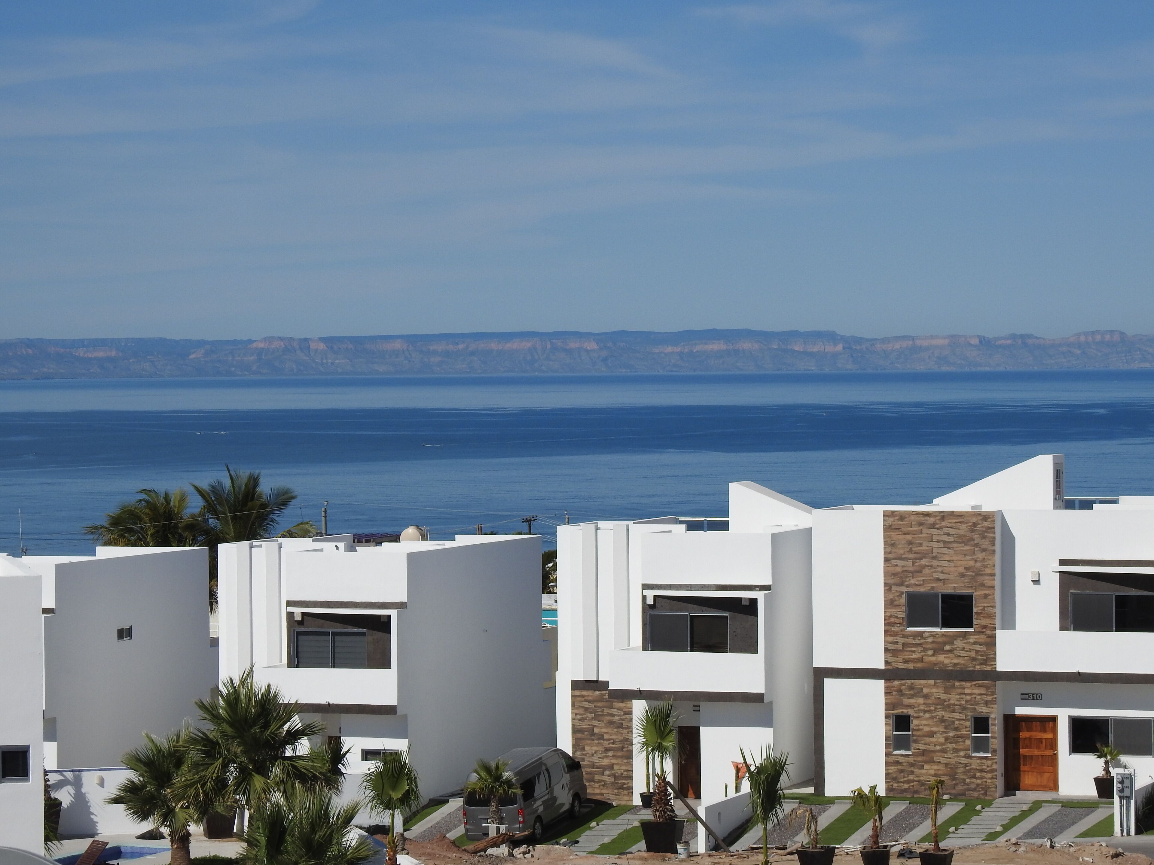 A modern building with a flat roof, white walls, and a stone accent wall.