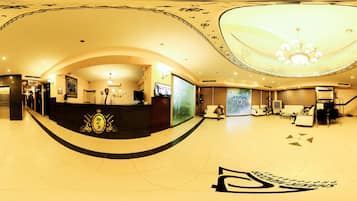 A spacious lobby with a reception desk, seating area, and a large chandelier.