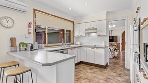 A modern kitchen with white cabinets, a large island, and a stone-patterned floor.