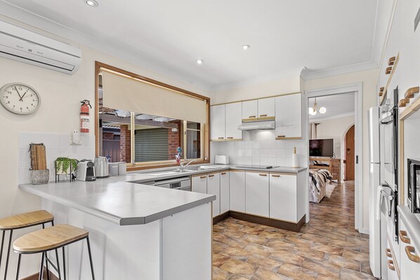 Una cocina moderna con armarios blancos, una isla central y un amplio ventanal.