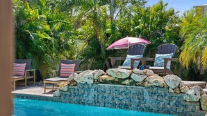 Un espace aménagé au bord de la piscine, avec des chaises longues et un mur décoratif en pierres.