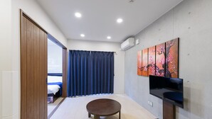 A modern hotel room with a bed, a round table, a TV, and a painting on the wall. - HOTEL Ciel Hills (Tokyo)