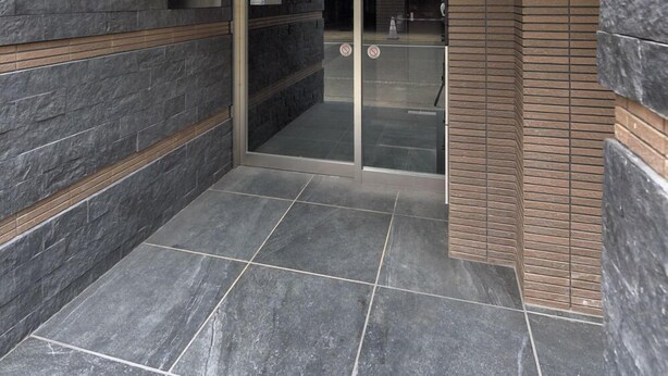 A modern hotel entrance with stone walls, a glass door, and a digital keycard reader. - HOTEL Ciel Hills (Tokyo)