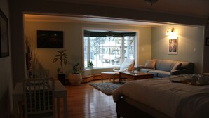 Une chambre à coucher avec un grand lit, une chaise, un canapé et une fenêtre donnant sur l’extérieur.