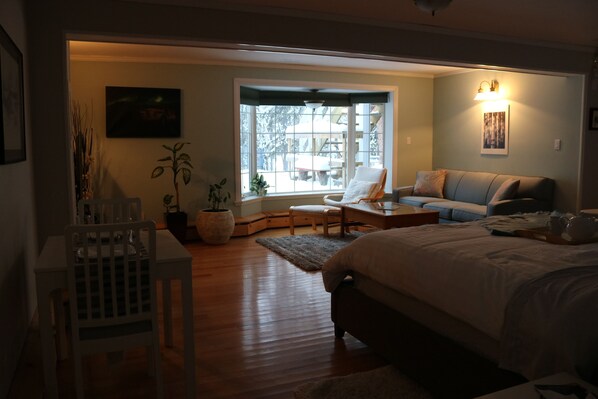 A bedroom with a large bed, a chair, a sofa, and a window with a view of the outside.