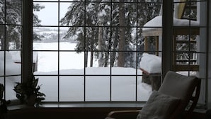 Une pièce dotée d’une grande fenêtre donnant sur un paysage enneigé, avec des arbres et une structure en bois.