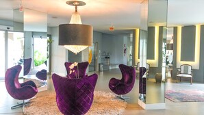 A modern interior with a round seating area, a chandelier, and a glass partition. - Apartamento de 2 Quartos no Luxuoso Condomínio Jay (Jurerê Internacional)